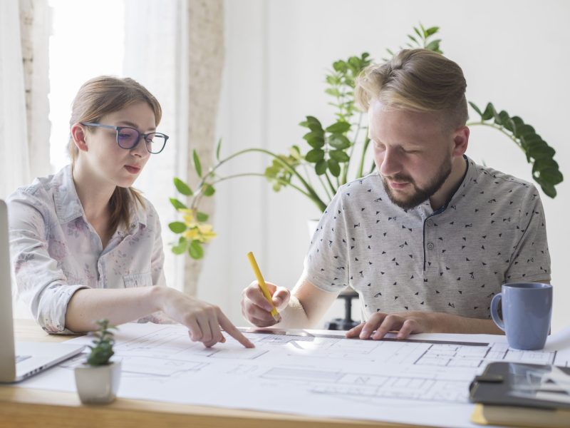 two-male-female-architect-working-blueprint-office